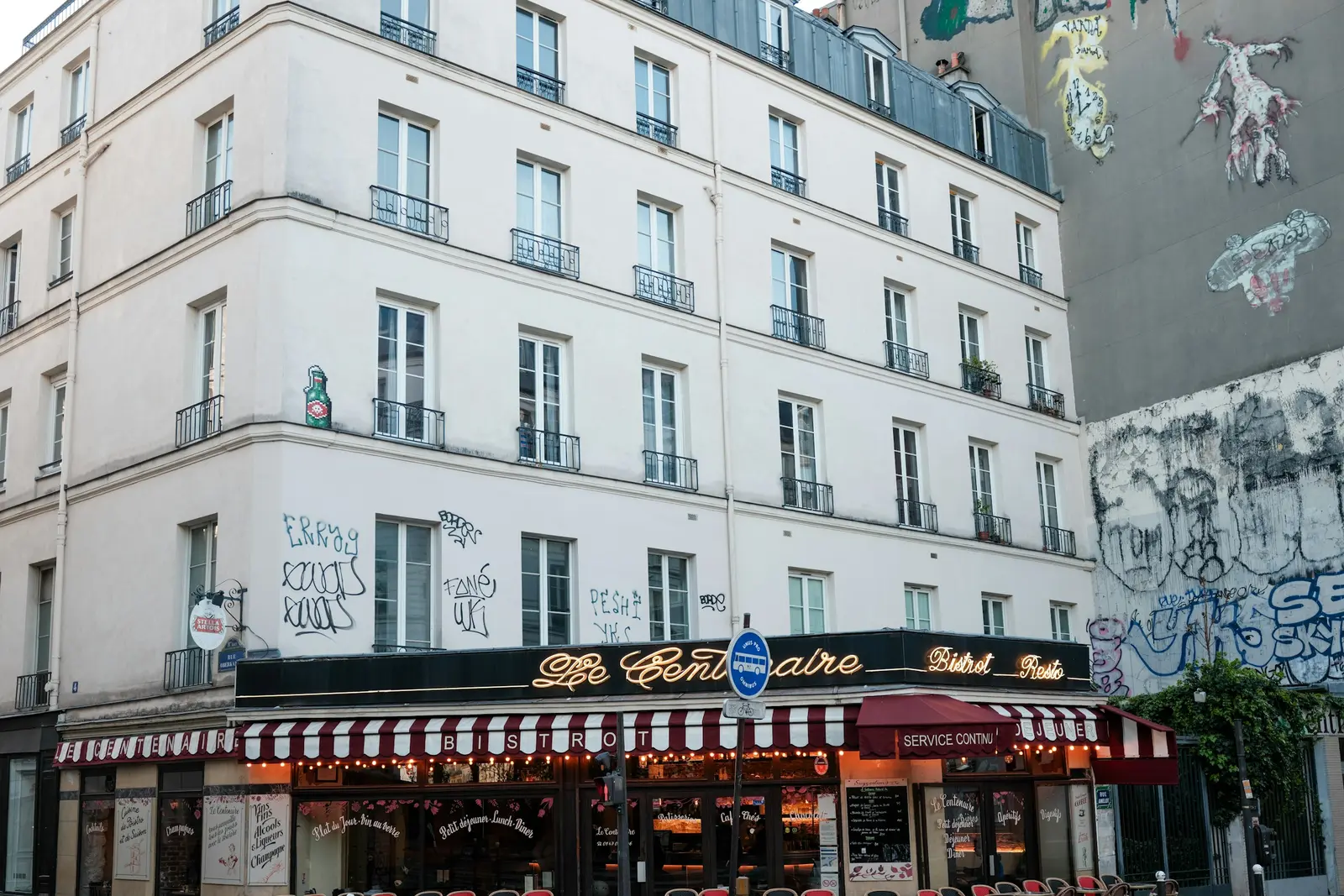 Street café with a red and white striped awning above pavement tables