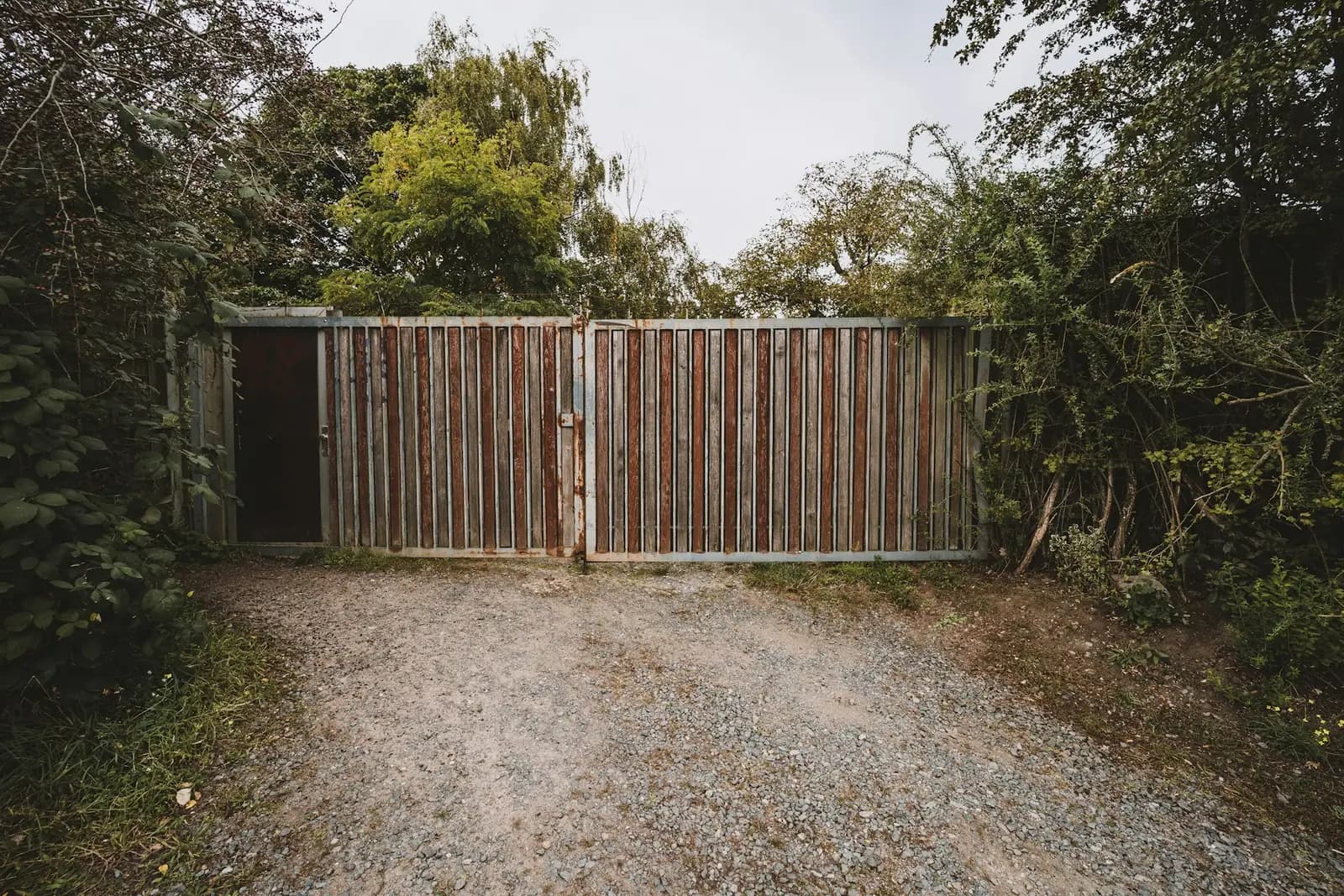 Closed timber driveway gates at the end of a gravel drive