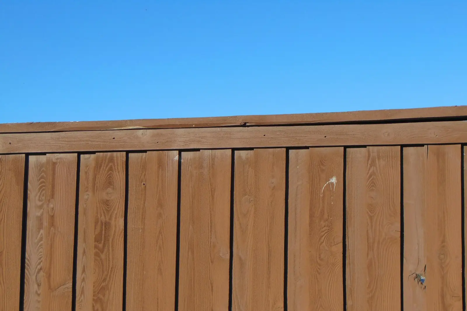 Timber fence panels against a blue sky