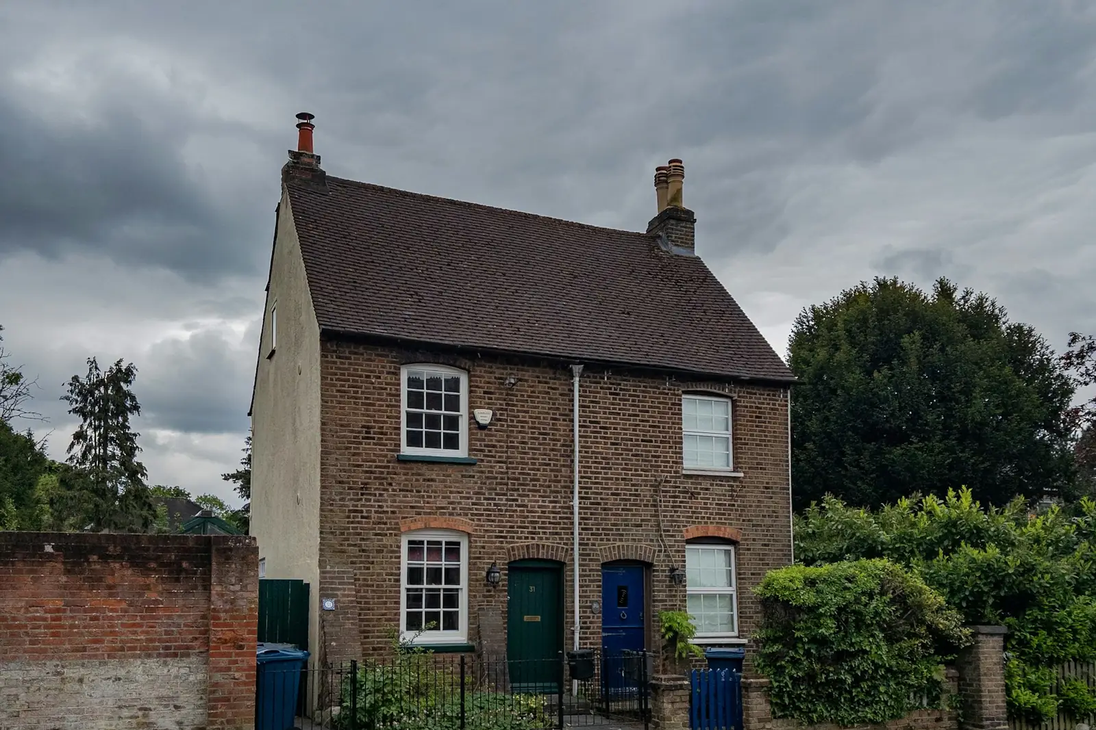 Brick cottage behind a low garden wall