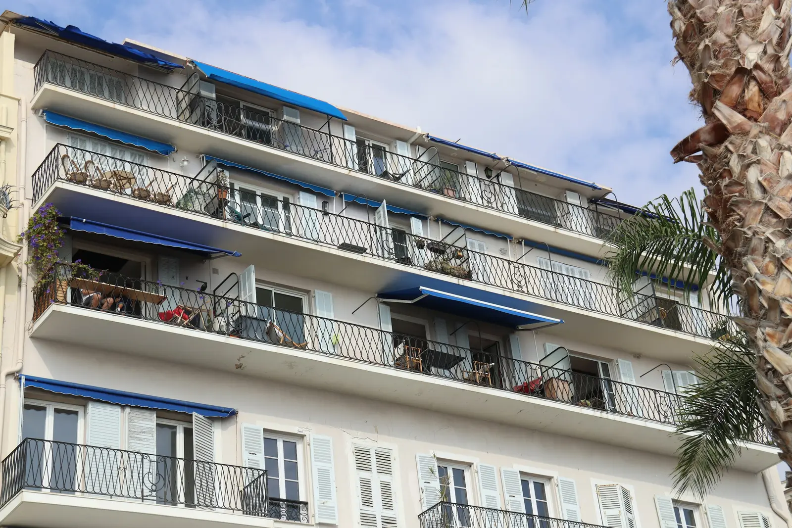 Blue fabric awnings over the balconies of a white apartment building