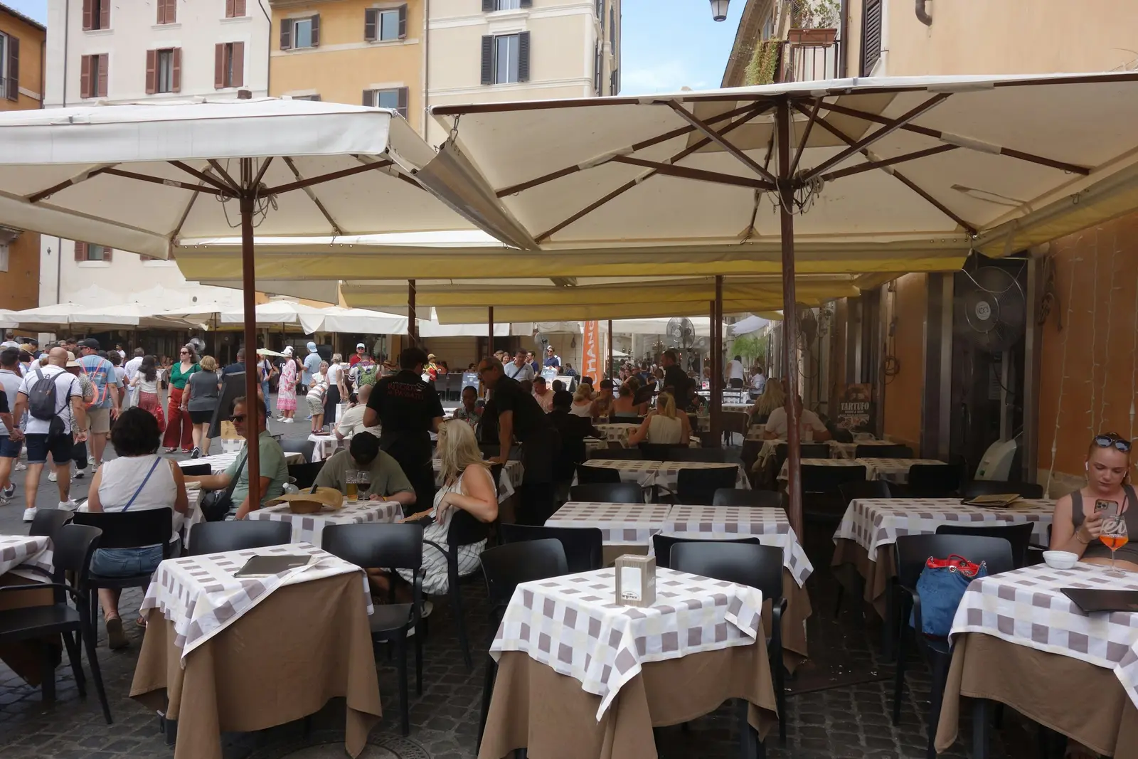 Large parasols over a busy outdoor restaurant terrace