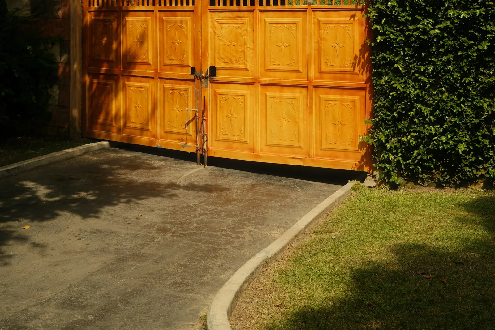 Tall timber driveway gates under a hedge archway