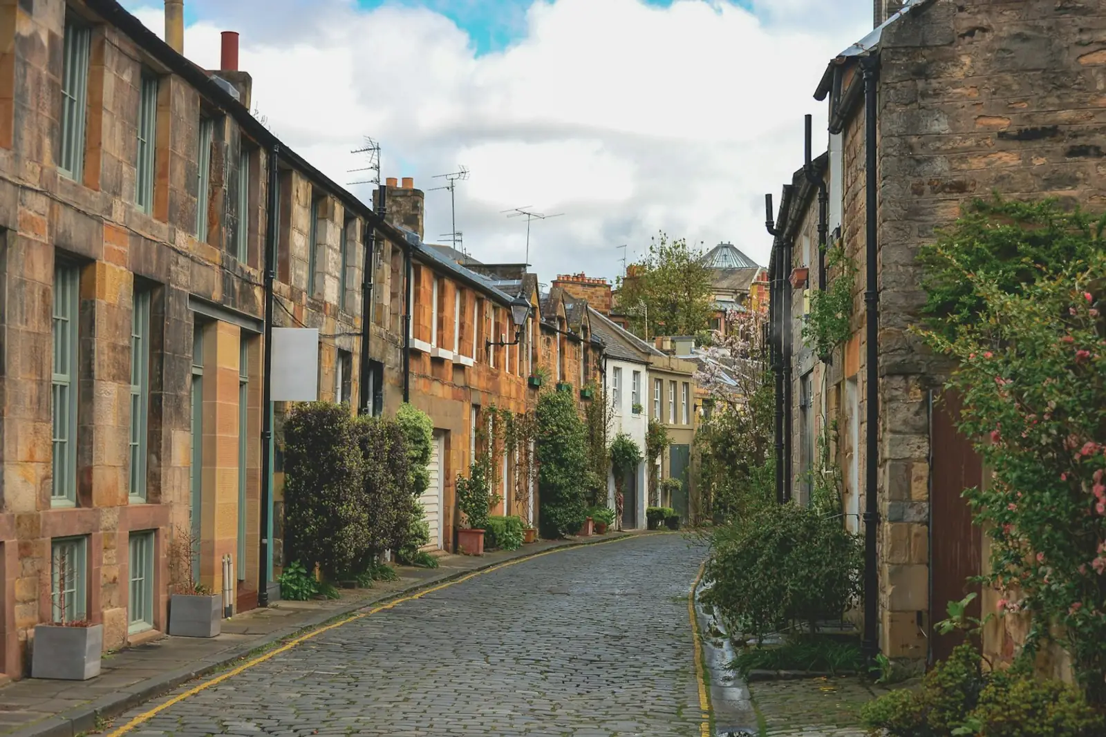 Cobbled mews lane lined with stone houses and climbing plants