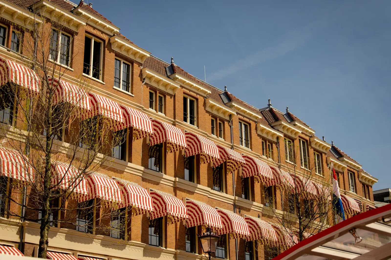 Rows of red and white striped window awnings on a brick building