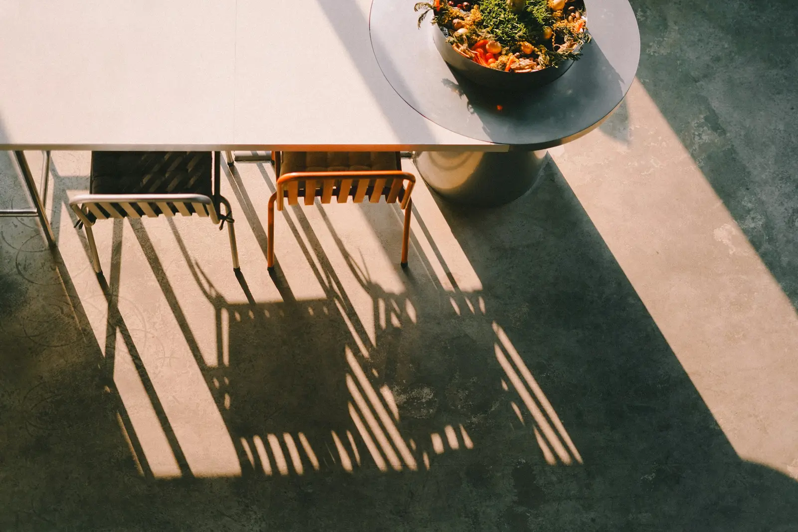 Strong sunlight casting long shadows across patio chairs and table