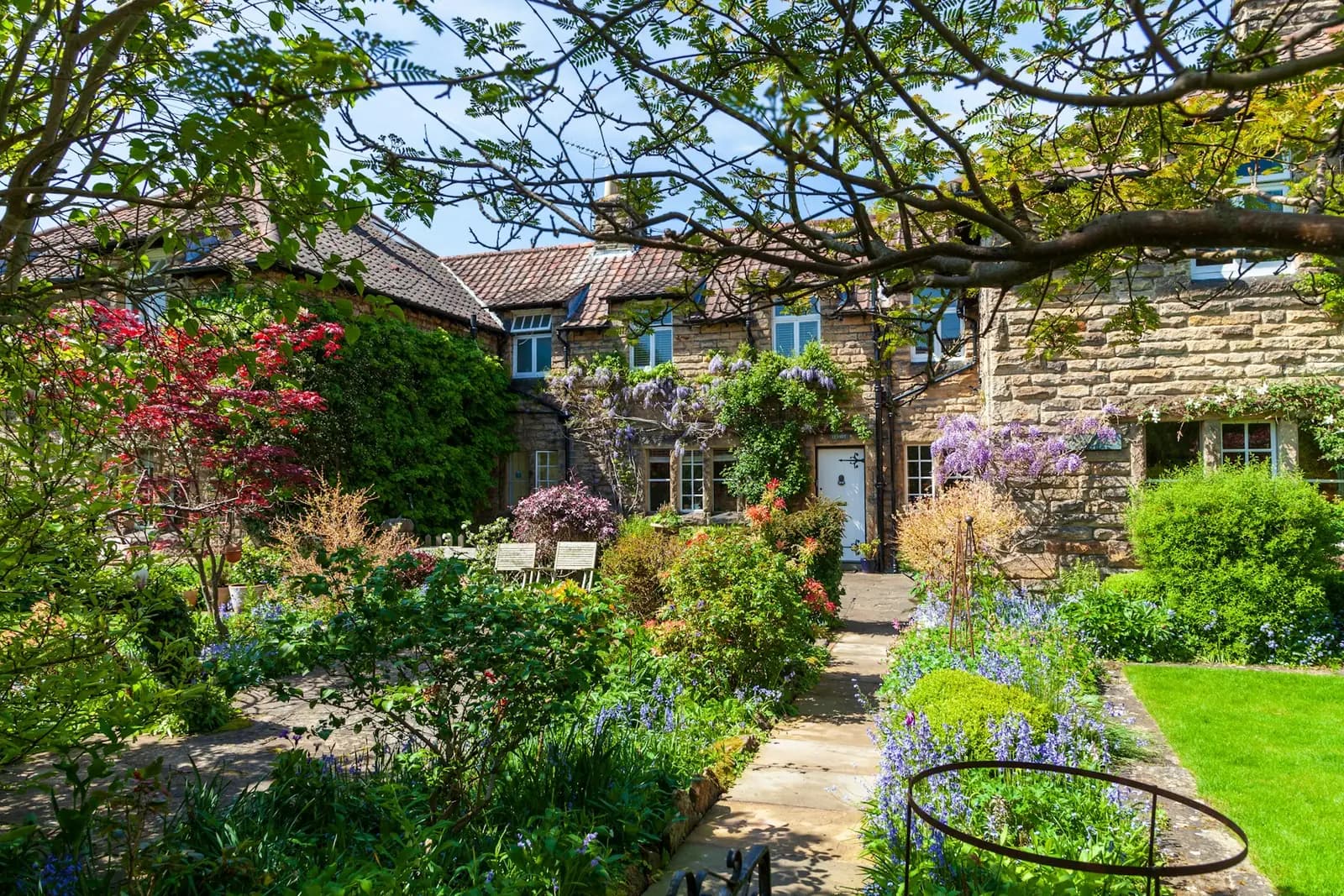 Cottage garden in full bloom in front of stone houses