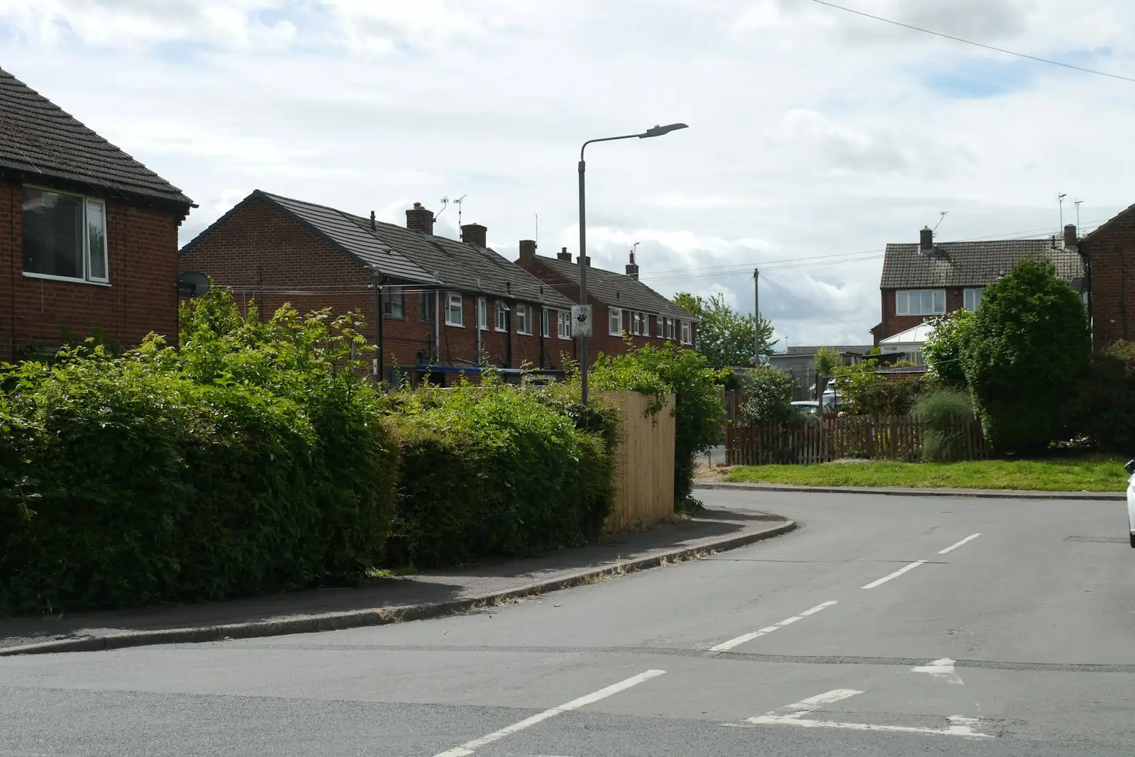 Suburban street of semi-detached houses with hedges and fences