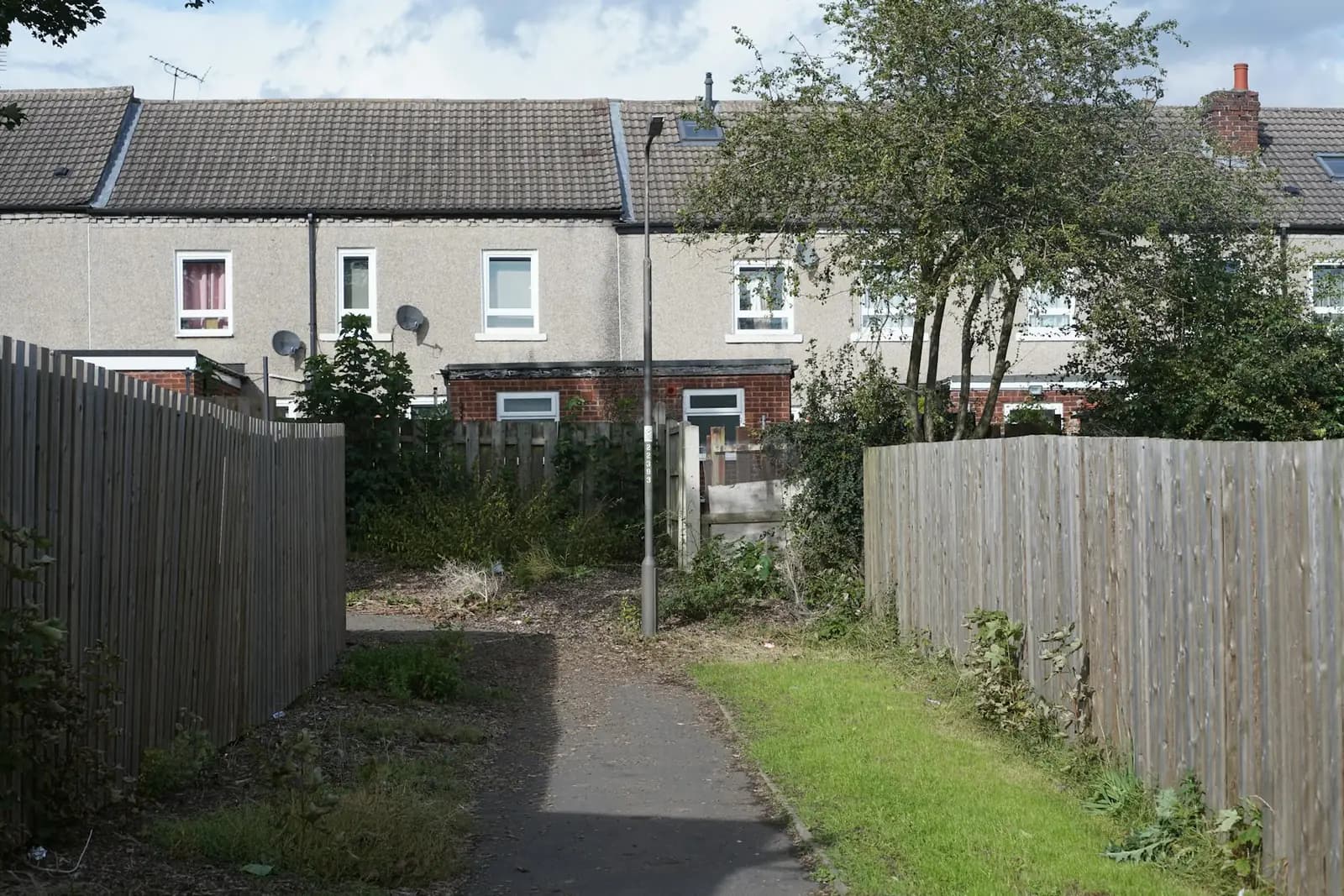 Back alley between garden fences behind terraced houses